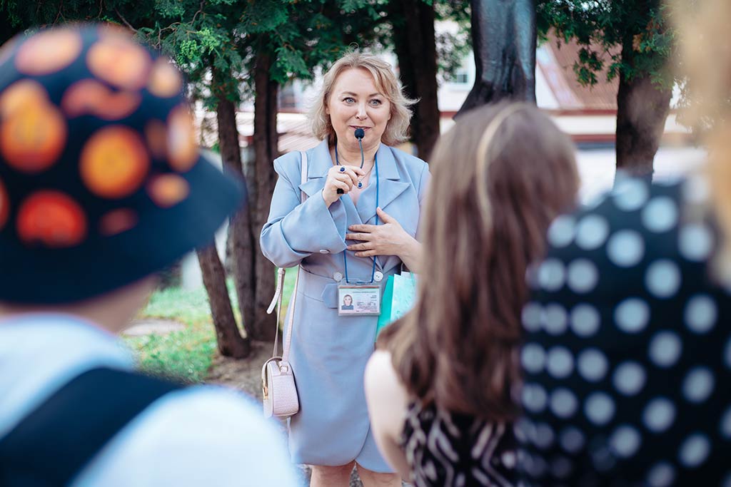 A female tour guide tells a group of female tourists exciting information about their destination.  